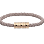 Beige braided cord bracelet with a gold segmented cylindrical clasp on black background.