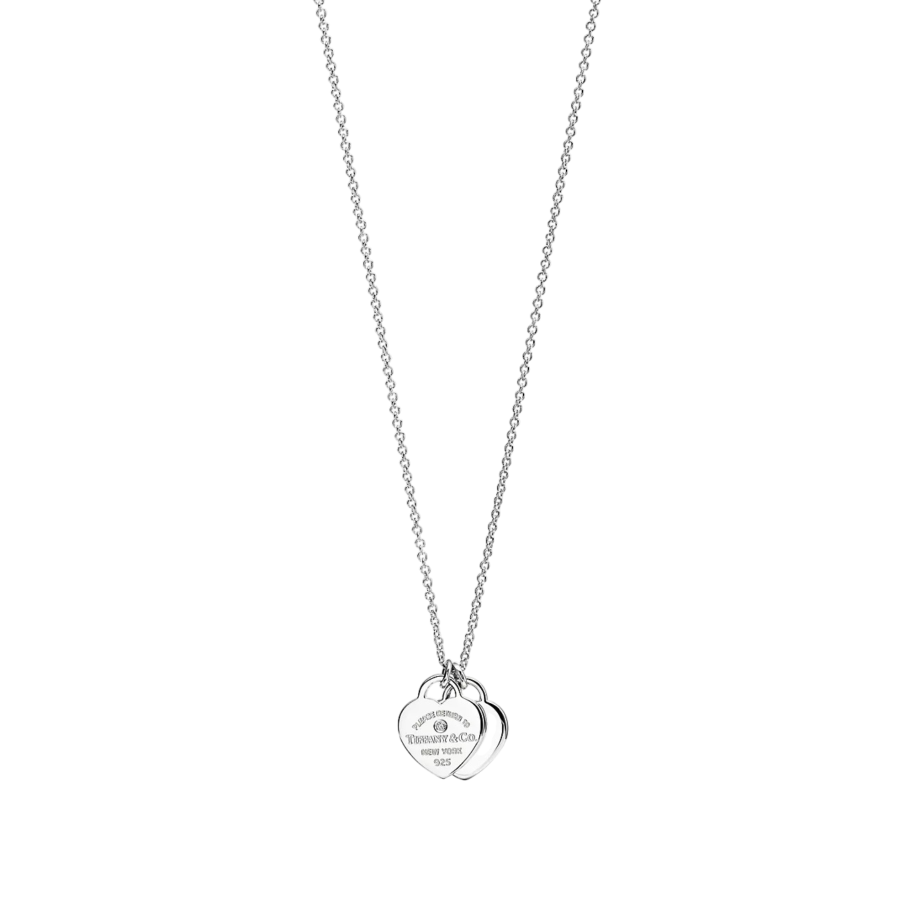 Silver chain necklace with two overlapping heart pendants, one engraved, hanging against a black background
