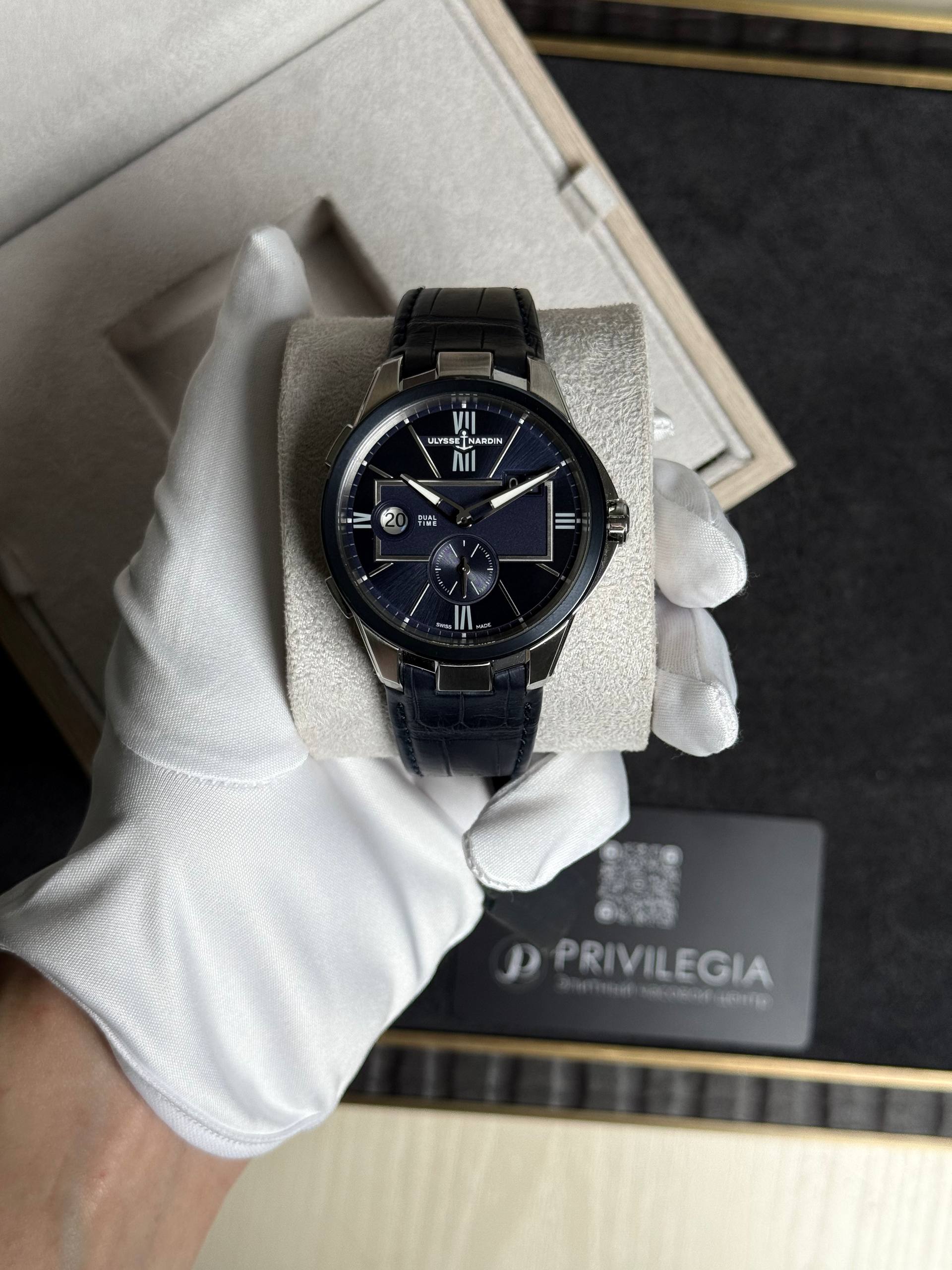 Luxurious blue-dial wristwatch with Roman numerals and subdial, held by a gloved hand in a presentation box.