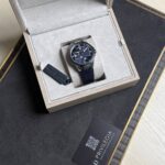 Ulysse Nardin wristwatch in a beige padded display box with a dark blue strap and blue dial.