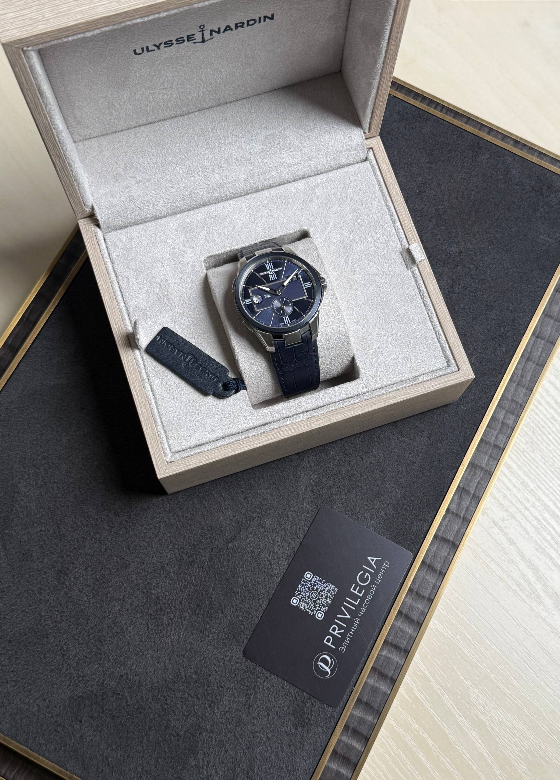 Ulysse Nardin wristwatch in a beige padded display box with a dark blue strap and blue dial.