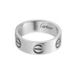 Close-up of a silver ring with 'Cartier' engraved on the inner rim, showing circular cutouts on the band.