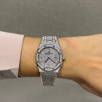 Diamond-encrusted Audemars Piguet watch worn on a wrist, with pavé diamonds on the dial and bracelet.