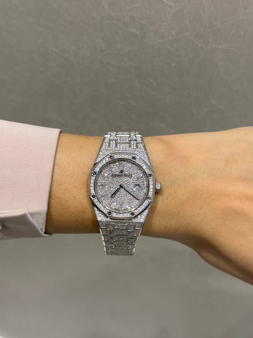 Diamond-encrusted Audemars Piguet watch worn on a wrist, with pavé diamonds on the dial and bracelet.