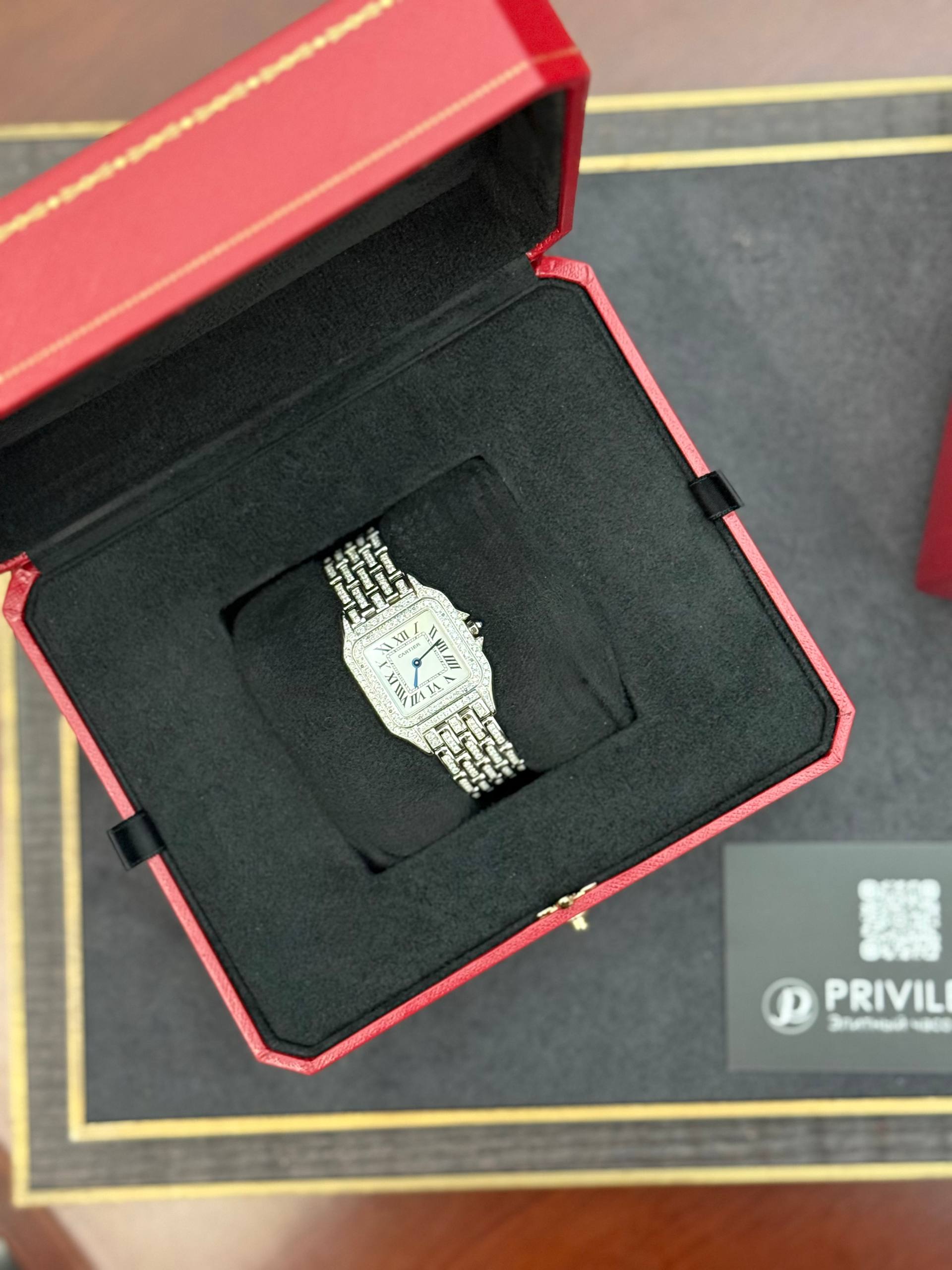 Silver wristwatch with a metal link bracelet displayed in an open red presentation box with a black interior.