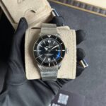 Breitling Superocean wristwatch with a metal mesh bracelet displayed on a beige suede cushion
