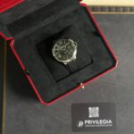 Cartier wristwatch in an open red presentation box with a black interior, showing a black dial with Roman numerals