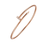 Rose gold open bangle bracelet with a small diamond-studded bar accent on a black background