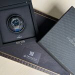Hublot wristwatch with blue strap in a black presentation box, the box open on a textured surface with a Privilegia card nearby