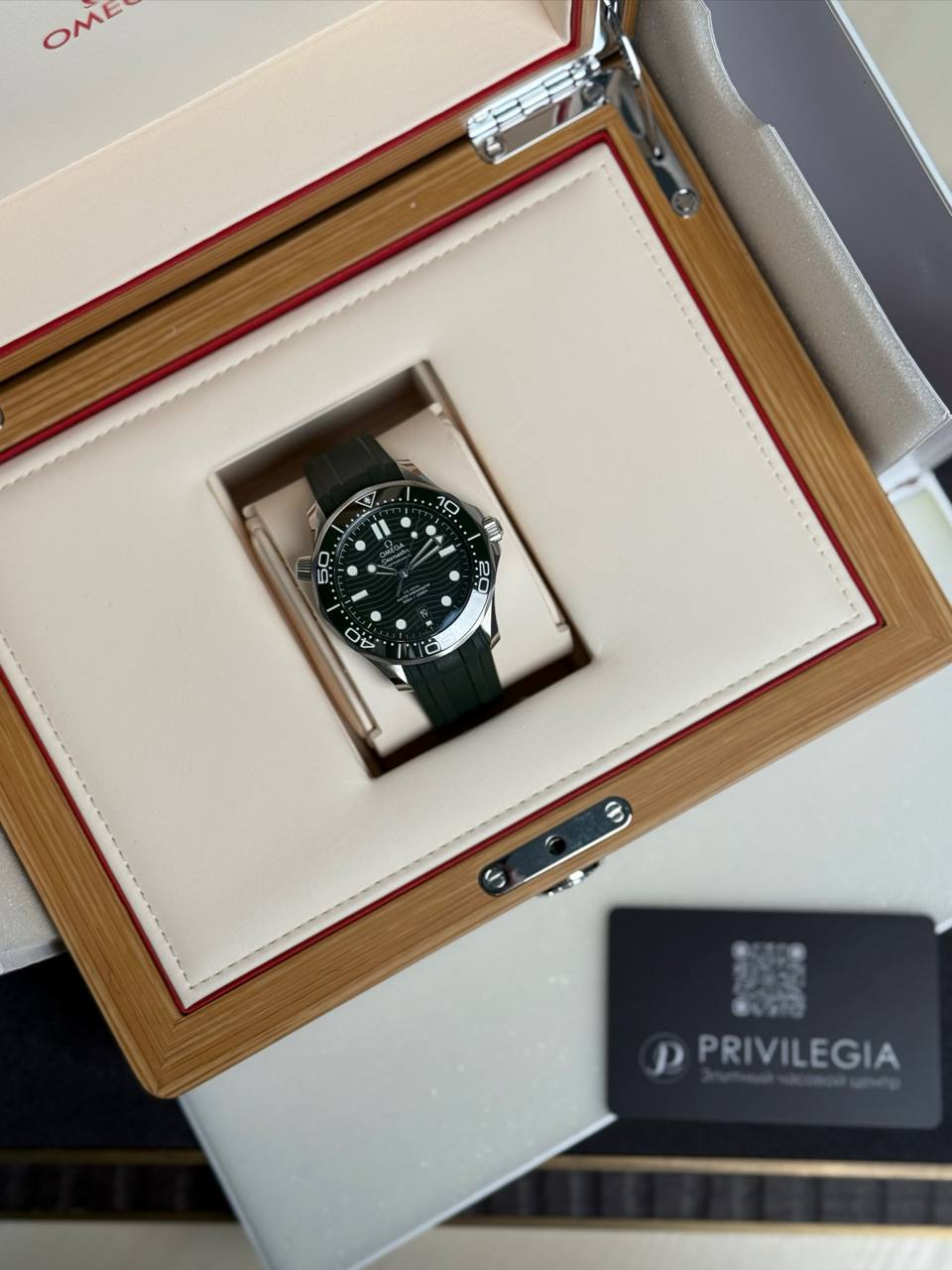 Omega dive watch with black dial in a wooden presentation box lined in cream, Privilegia card nearby