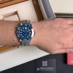 Omega Seamaster stainless steel watch with blue dial and bezel on a wrist.