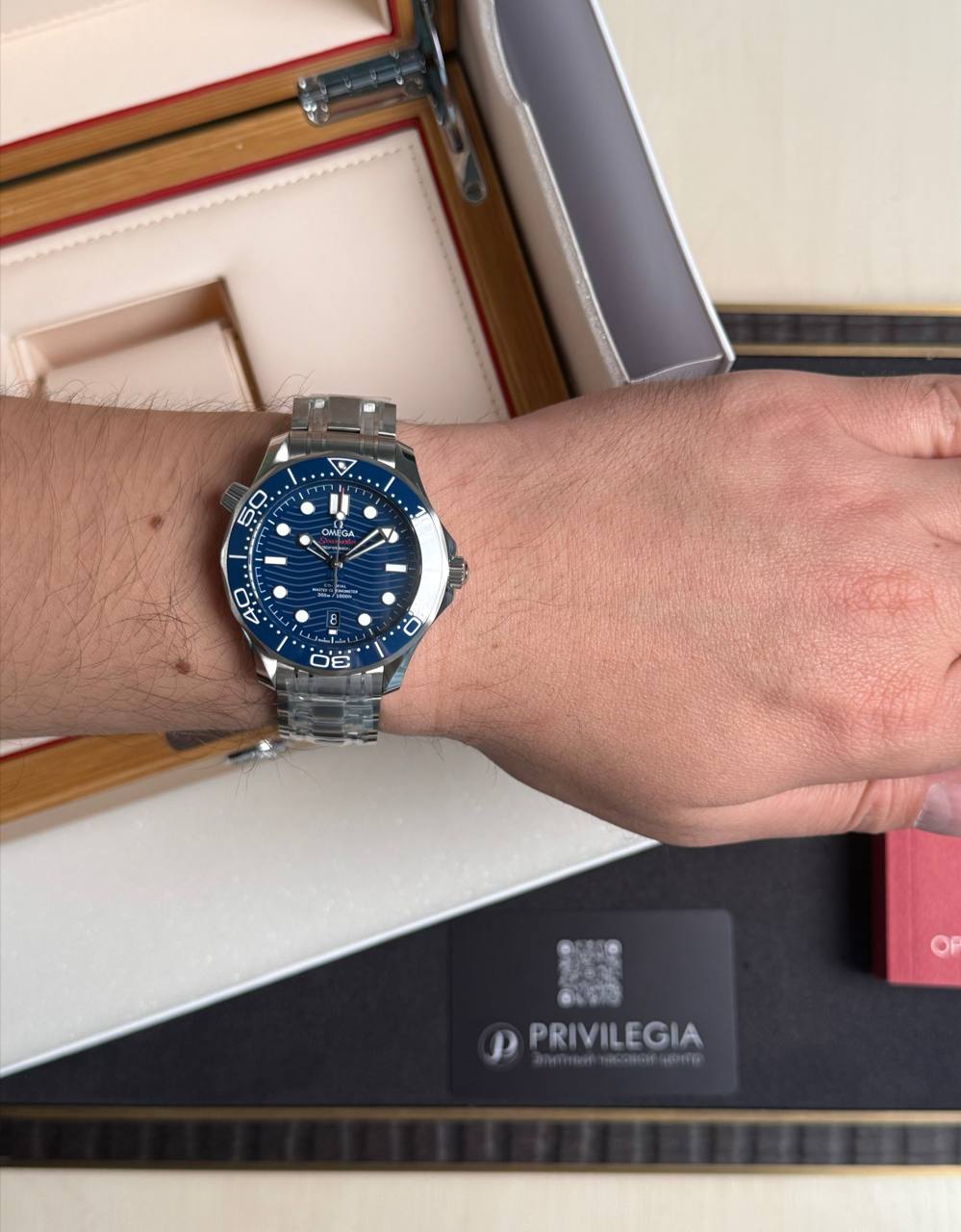 Omega Seamaster stainless steel watch with blue dial and bezel on a wrist.