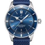 Blue Breitling SuperOcean wristwatch with a textured blue strap and silver case, showing a blue dial and date window at 6 o'clock on a black background.