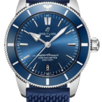 Blue Breitling SuperOcean wristwatch with a textured blue strap and silver case, showing a blue dial and date window at 6 o'clock on a black background.