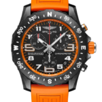 Breitling chronograph watch with black dial and bright orange strap, bold numerals and multiple subdials on black background.