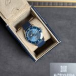 Blue dive-style wristwatch with a matching blue strap in an open beige display box.