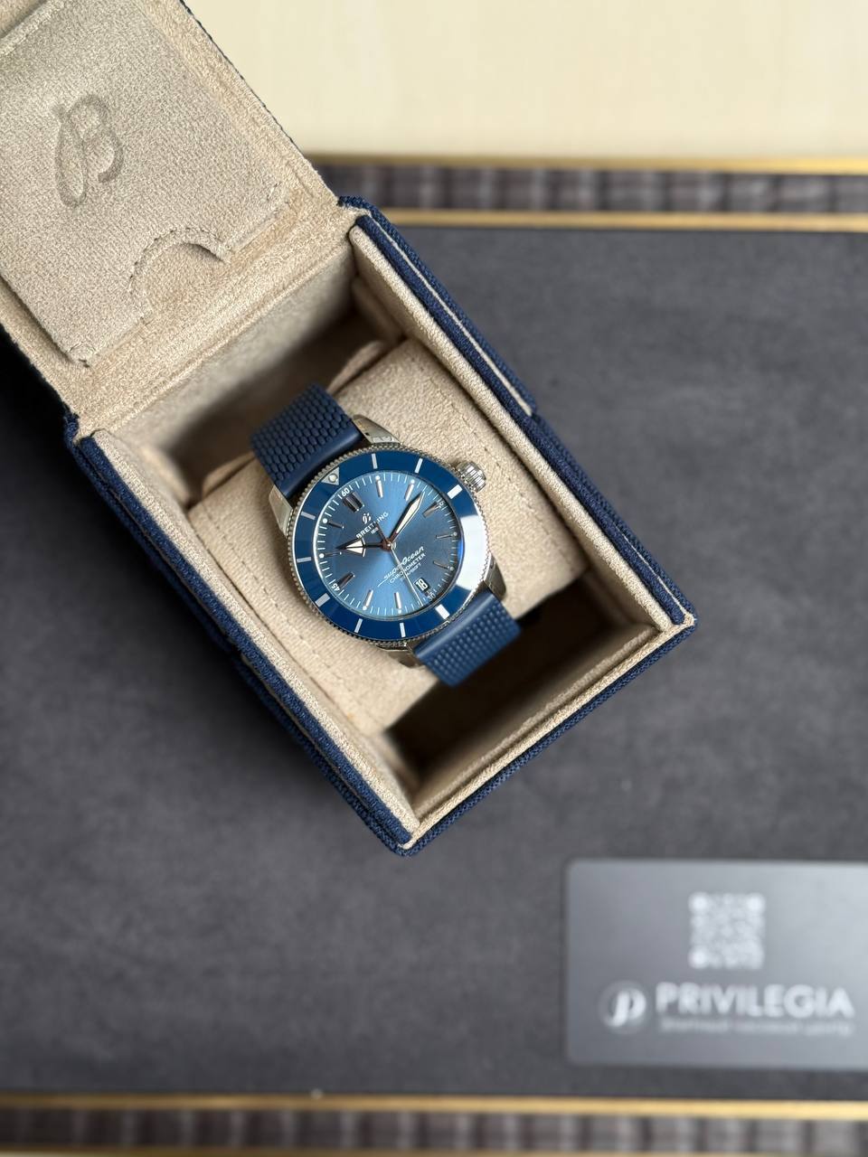 Blue dive-style wristwatch with a matching blue strap in an open beige display box.