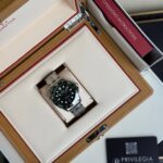 Omega diver-style stainless steel watch displayed in an opened wooden presentation box with a white interior and red trim, instruction booklet nearby