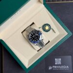 Rolex GMT-Master II watch with blue/black bezel in an open green presentation box with green seal tag nearby.