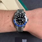 Wrist wearing a stainless steel Rolex GMT-Master II with a black dial and blue/black bezel, date window at 3 o'clock.
