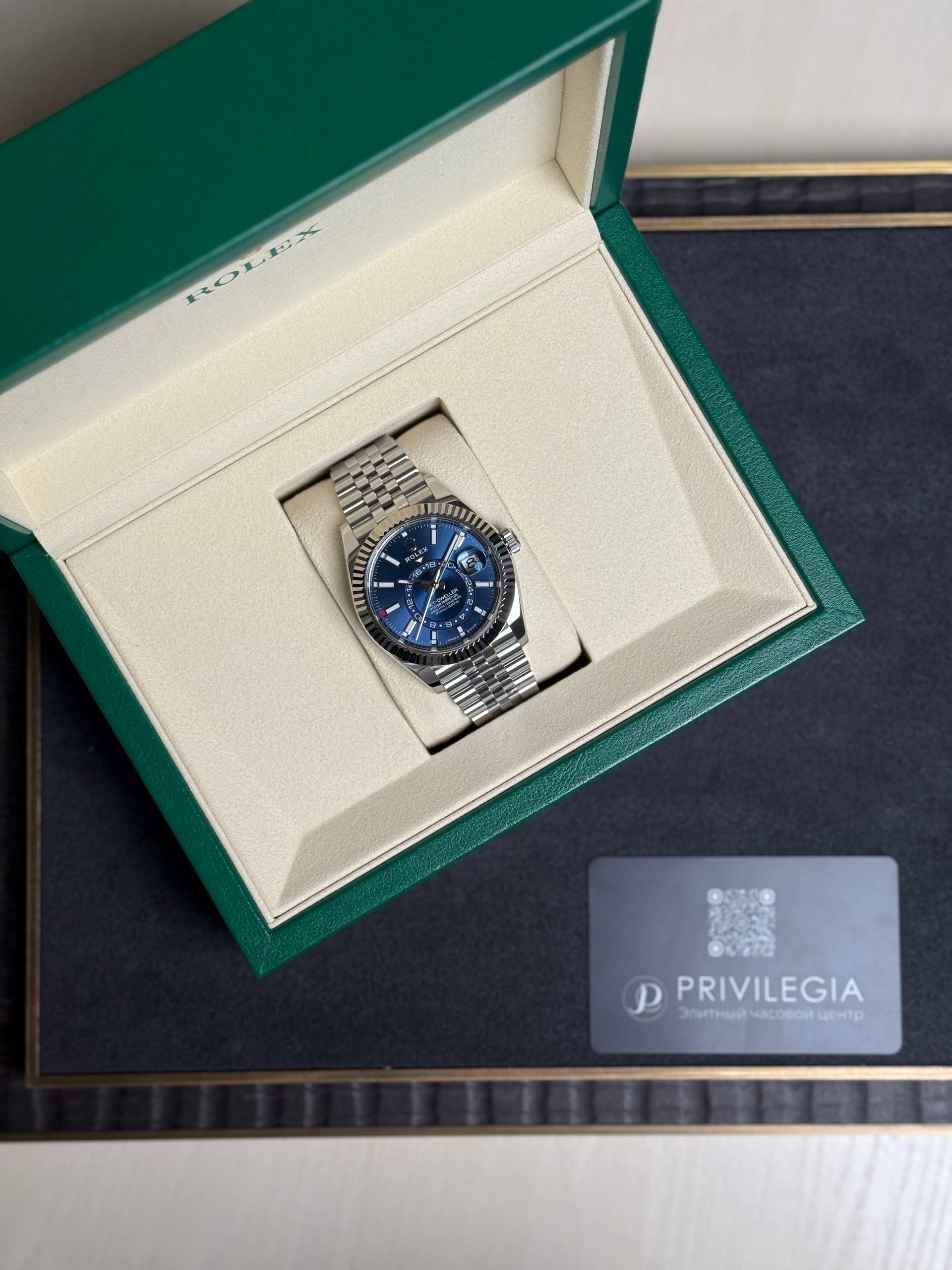 Rolex watch with blue dial in an open green presentation box.