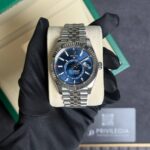 Rolex Sky-Dweller stainless steel watch with a blue dial in a green box, held by gloved hand