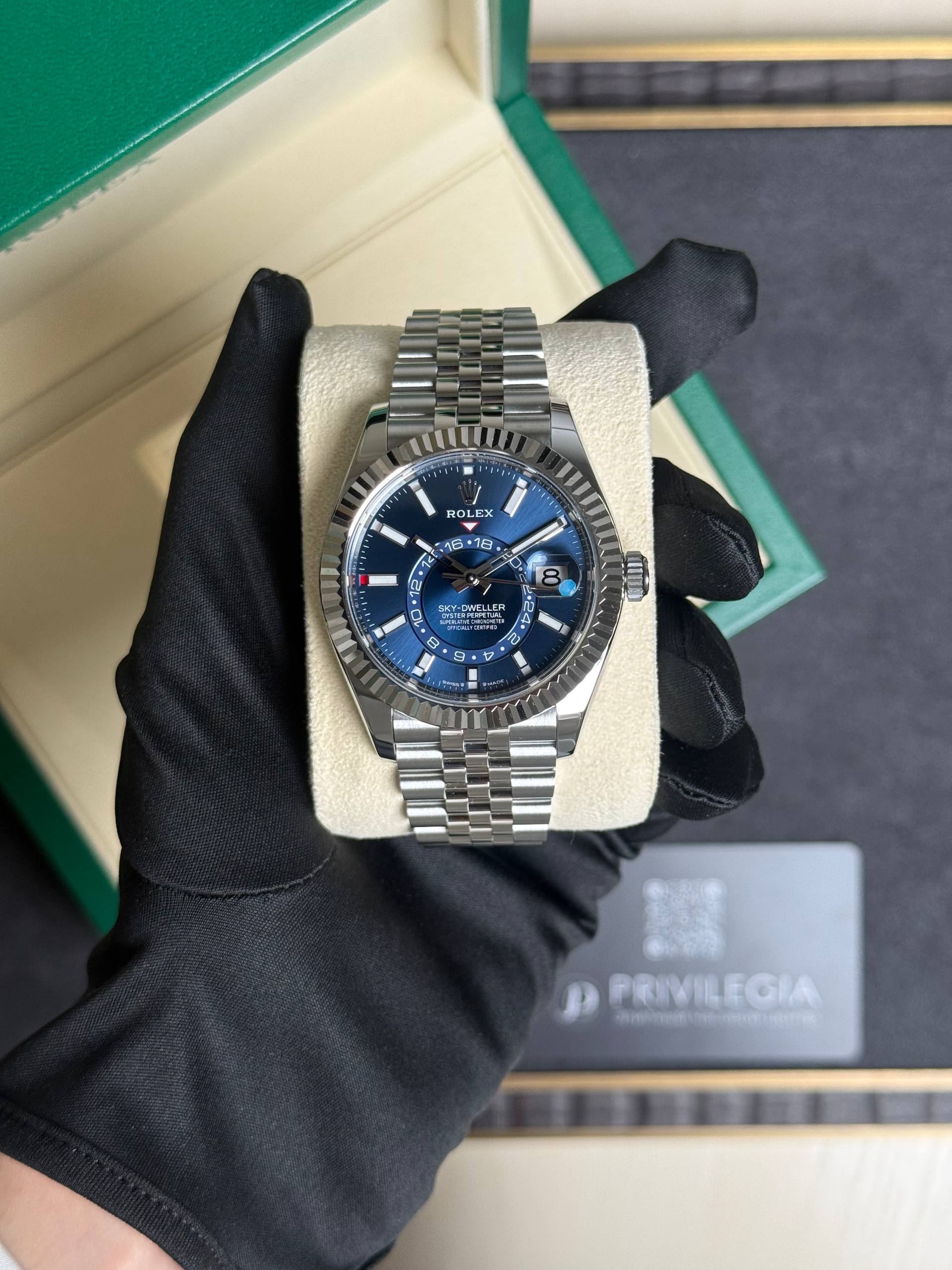 Rolex Sky-Dweller stainless steel watch with a blue dial in a green box, held by gloved hand