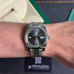 Stainless steel Rolex Datejust on a wrist, with green Roman numeral markers and a date window at 3 o'clock.