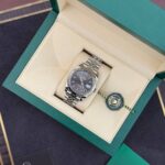 Rolex Oyster Perpetual Datejust in a green presentation box with cream interior and a hanging Rolex tag