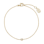 Gold bracelet with a small bezel-set diamond at the center on a thin chain against a black background, jewelry product image.