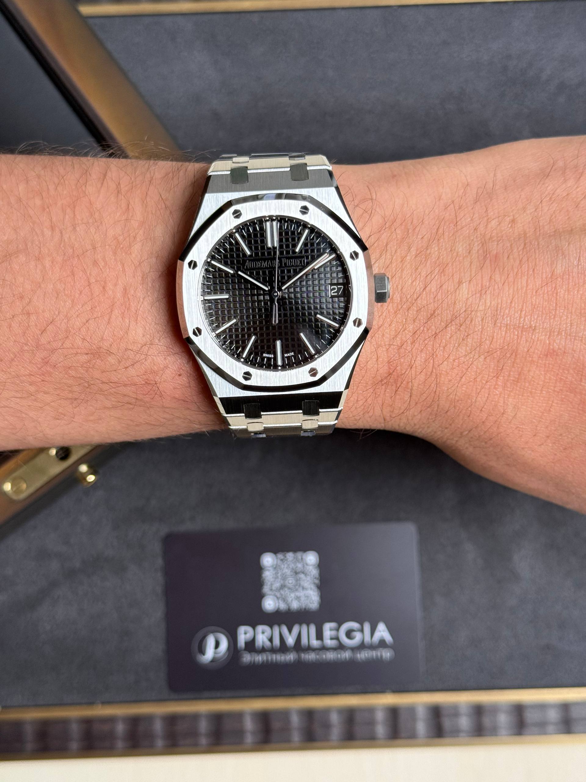 A stainless steel Audemars Piguet Royal Oak wristwatch with a black textured dial and date window on the wrist.