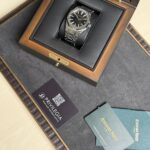 Stainless steel wristwatch in a black-lined wooden presentation box, with the Audemars Piguet logo on the black dial.