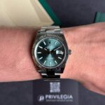 Rolex Datejust on wrist with green sunburst dial, fluted bezel, stainless steel bracelet, date window at 3.