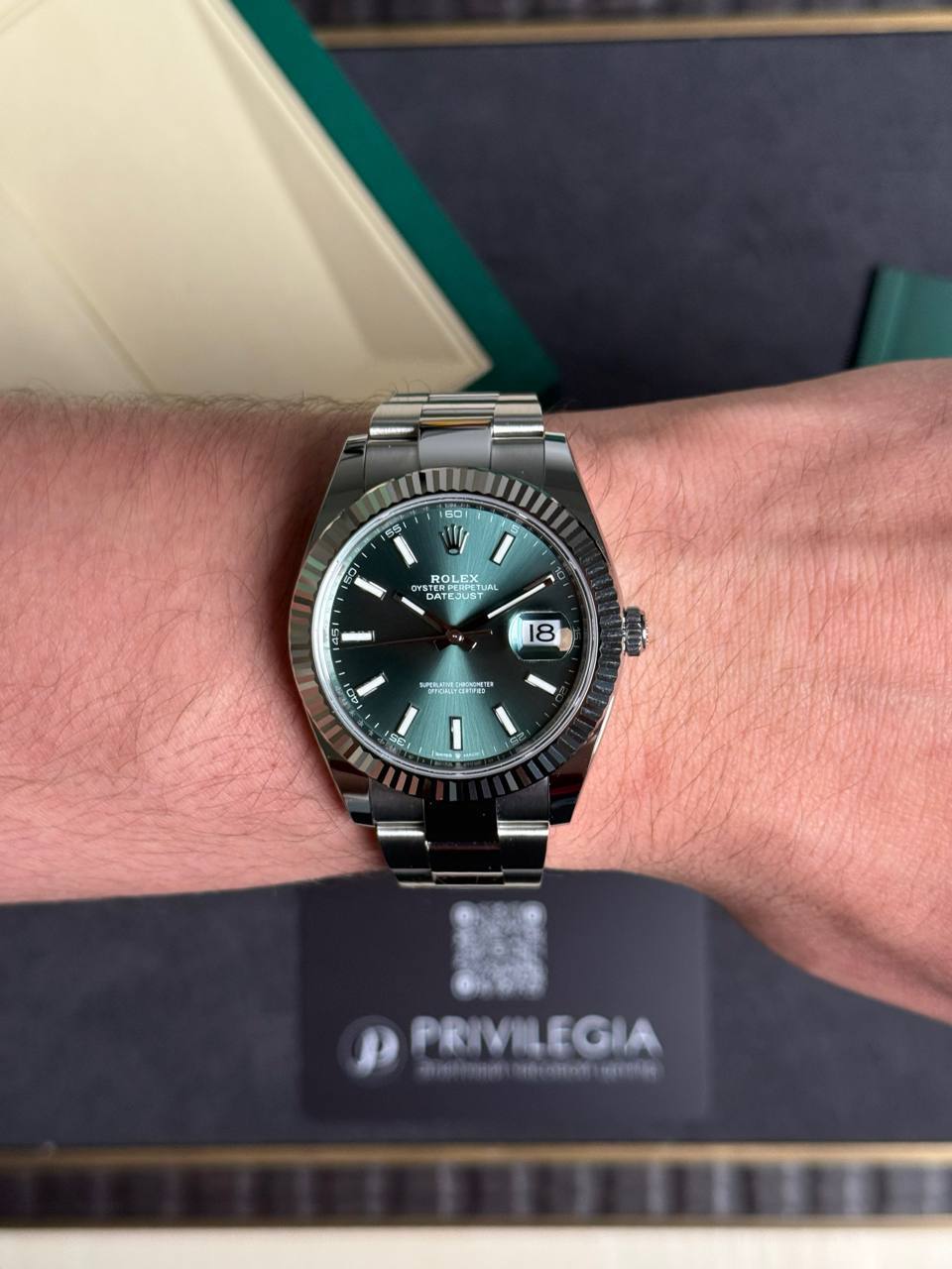 Rolex Datejust on wrist with green sunburst dial, fluted bezel, stainless steel bracelet, date window at 3.