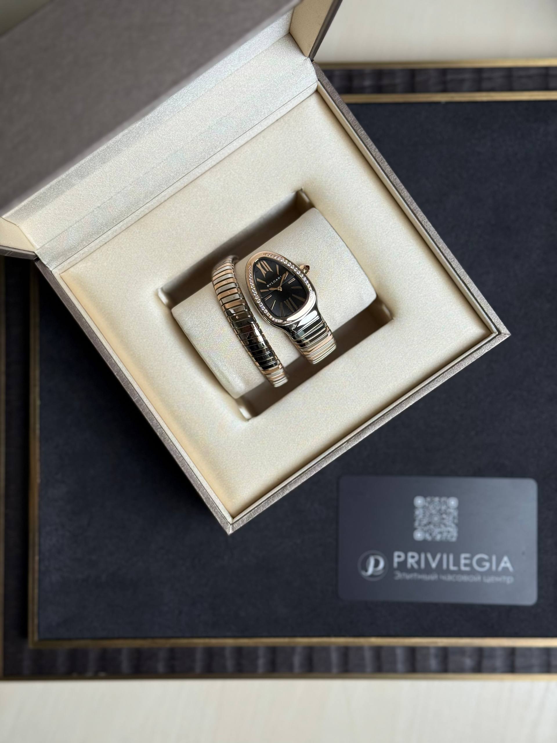 Gold and silver wristwatch with diamond-studded bezel in an open jewelry box, cream lining and a Privilegia card nearby