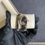 Bulgari wristwatch with an oval black dial and diamond bezel, held in a gloved hand on a beige cushioned case.