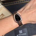 Woman wearing a silver Bulgari wristwatch with a black dial and diamond-studded bezel on the wrist.
