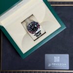 Rolex GMT-Master II in a green presentation box on a beige insert, with a Privilegia card nearby.