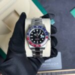 Stainless steel Rolex GMT‑Master II on a display pillow, blue‑red bezel and black dial under a gloved hand pocketed in a box.