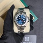 Rolex stainless steel dive watch with blue dial and date window, held in a gloved hand on a beige cushion.