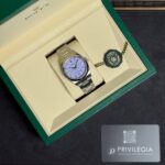 Rolex stainless steel watch in a green and beige presentation box with attached green tag and ring seal