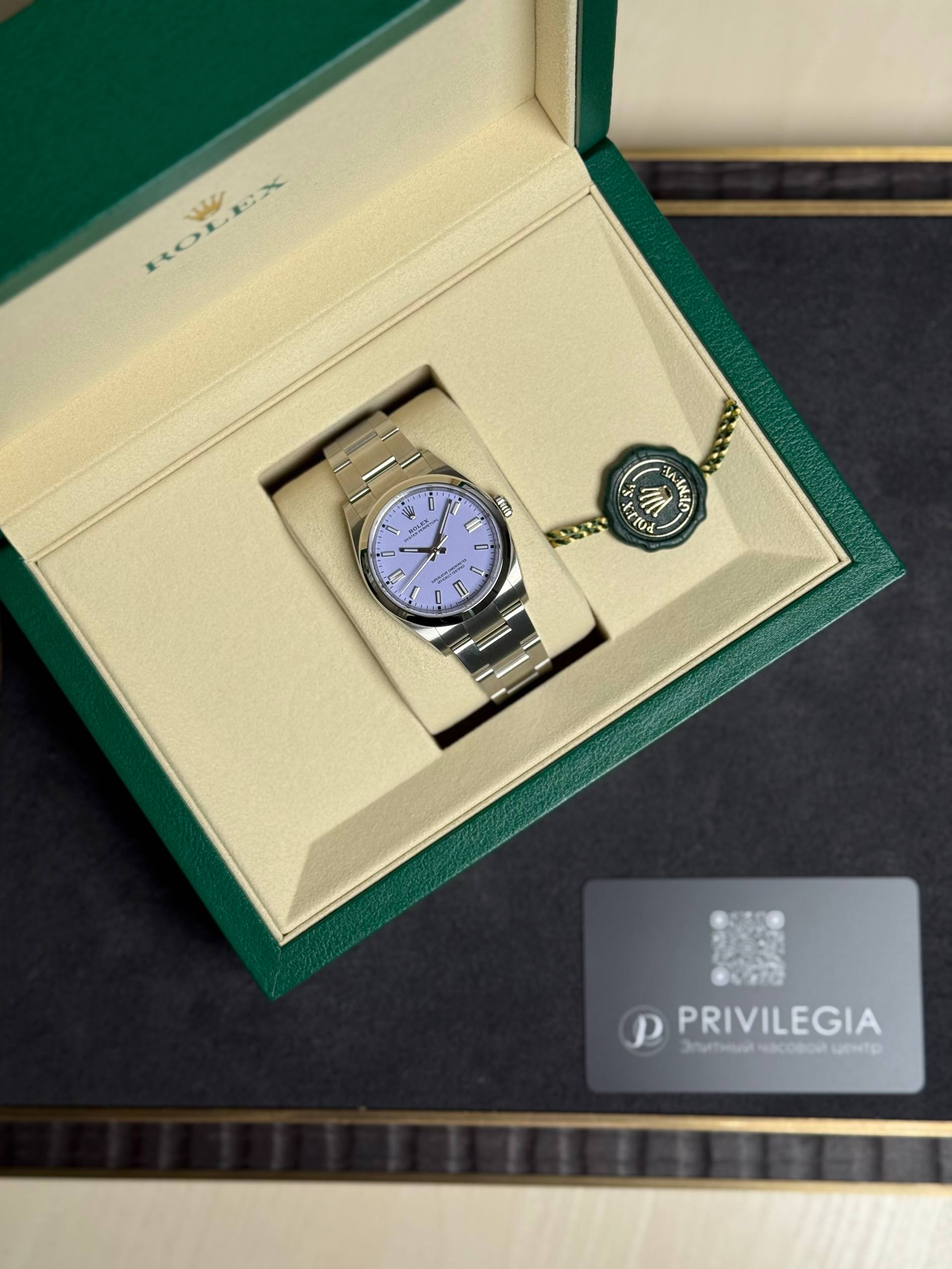 Rolex stainless steel watch in a green and beige presentation box with attached green tag and ring seal