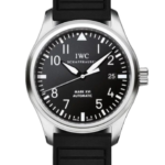 IWC pilot watch with black dial, white numerals, and stainless steel case on a black rubber strap showing date at 3 o'clock