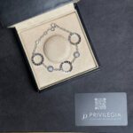 Silver Bulgari bracelet with circular links displayed in a beige jewelry box inside a black case.