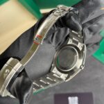 Close-up of a stainless steel Rolex watch bracelet on black fabric, with the deployment clasp and logo visible.