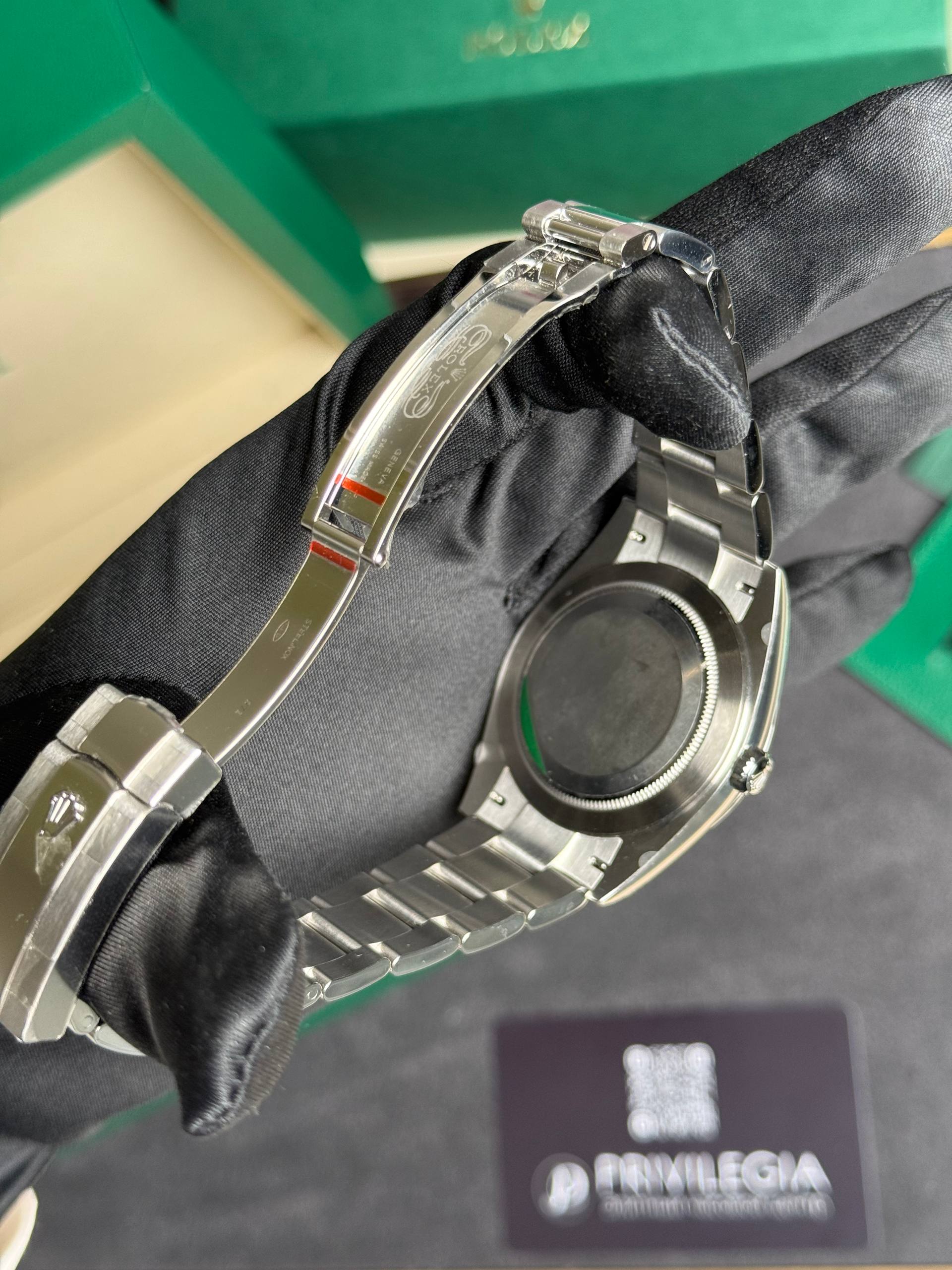 Close-up of a stainless steel Rolex watch bracelet on black fabric, with the deployment clasp and logo visible.