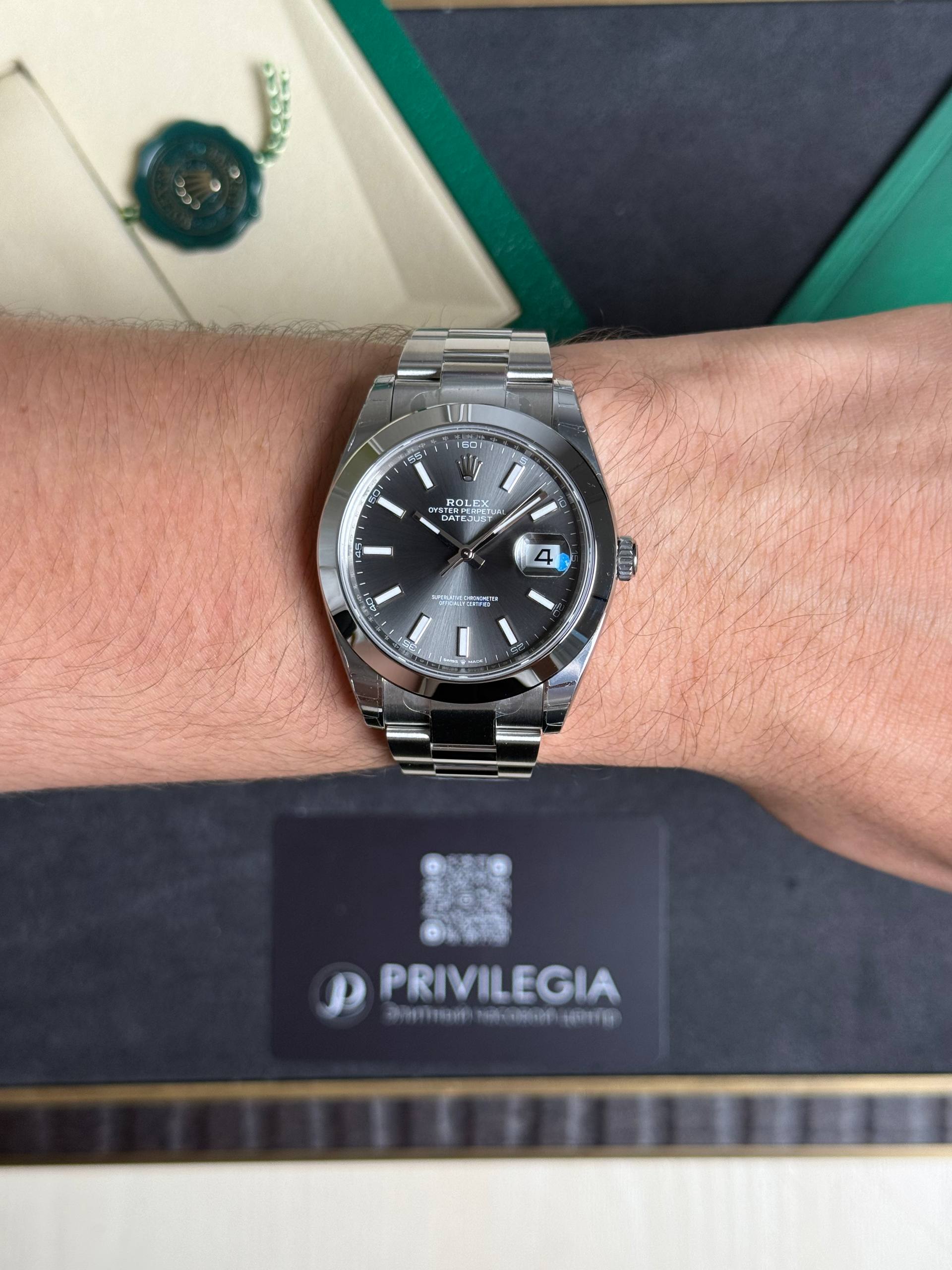 Close-up of a silver Rolex Datejust on a man's wrist, showing the dark dial and date window at 3 o'clock