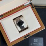 Omega watch in an open wooden box with cream interior and red trim, Privilegia card nearby