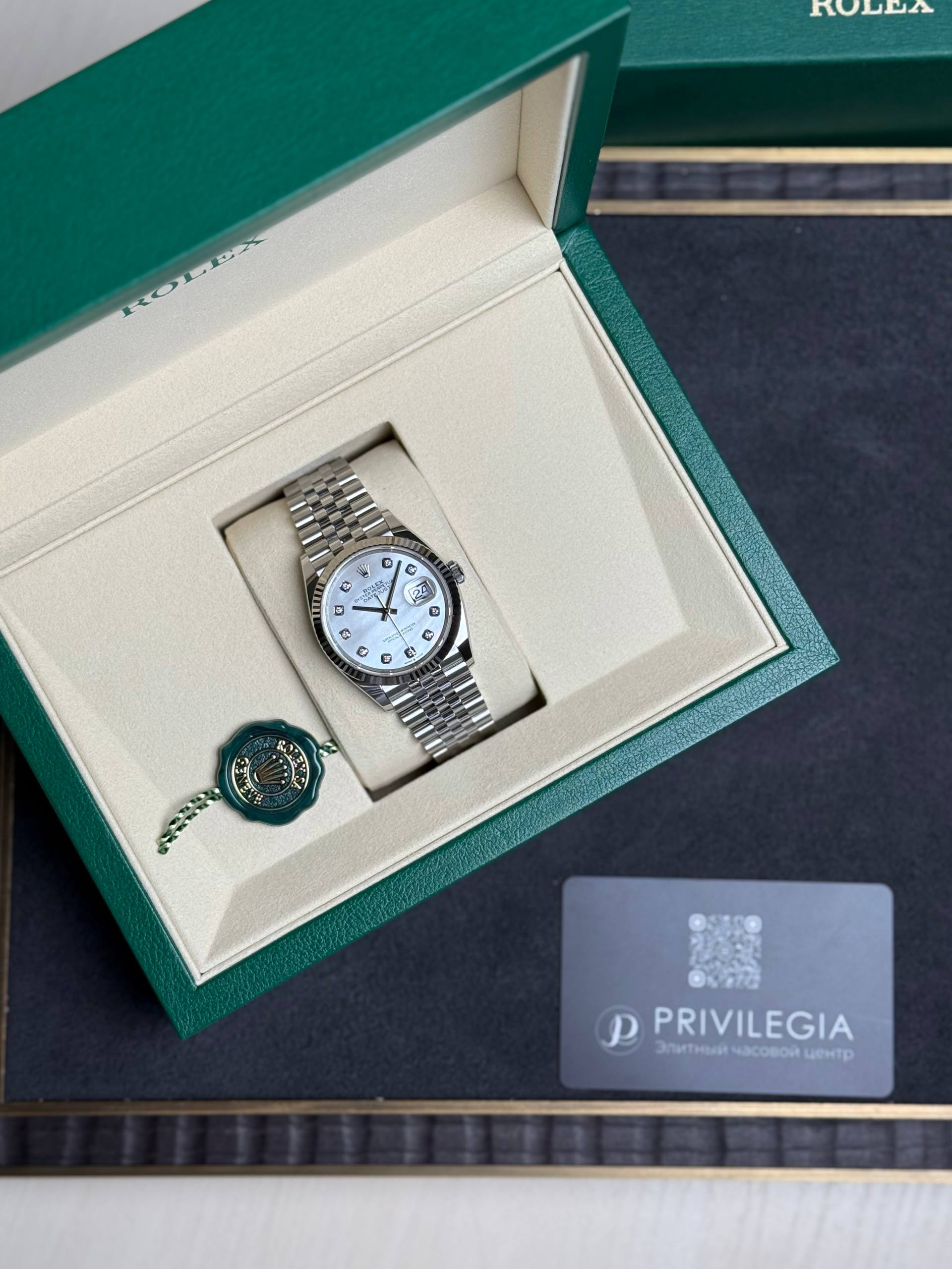 Rolex watch in its green presentation box with a beige interior, green seal, and Privilegia card on a dark surface.