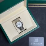 Rolex wristwatch in beige interior of green presentation box, partial view of outer box and a Privilegia card nearby